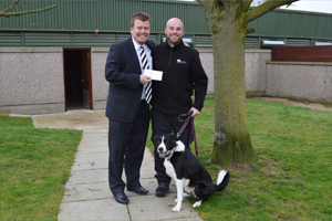 Managing Director, Haydn Davies, hands over a cheque to Neil and Sam the collie of Mrs Murray's Home for Stray Dogs and Cats.